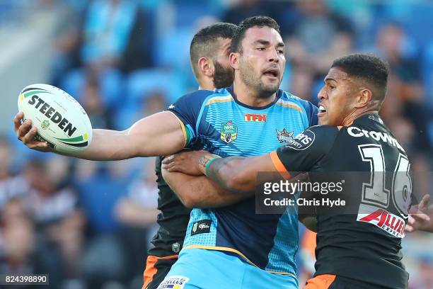 Ryan James of the Titans offloads while tackled during the round 21 NRL match between the Gold Coast Titans and the Wests Tigers at Cbus Super...