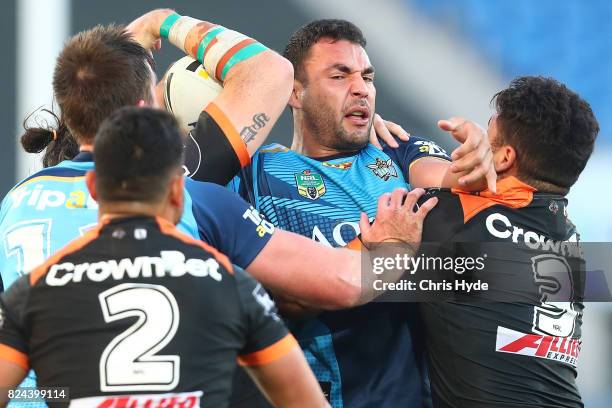 Ryan James of the Titans is tackled during the round 21 NRL match between the Gold Coast Titans and the Wests Tigers at Cbus Super Stadium on July...