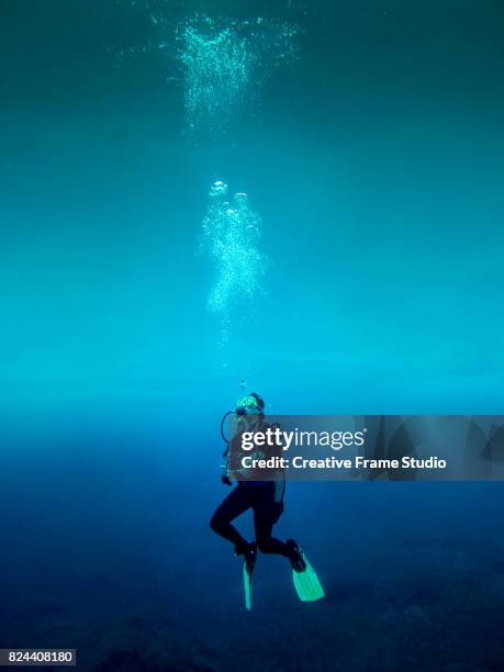 scuba diver standing still in the ocean void - buceo con equipo fotografías e imágenes de stock