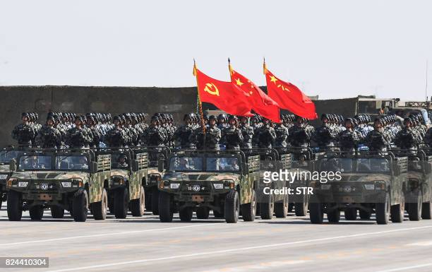 Chinese soldiers carry the flags of the Communist Party, the state, and the People's Liberation Army during a military parade at the Zhurihe training...