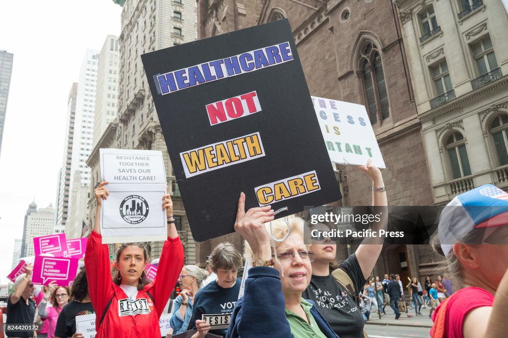 Participants hold signs while protesting the repeal and...