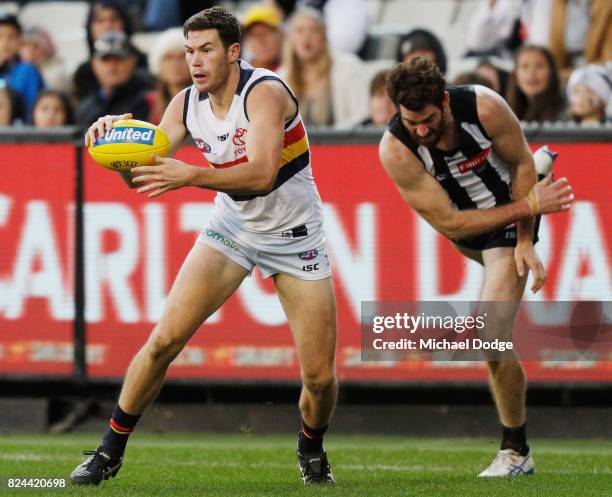 Mitchell McGovern of the Crows runs with the ball away from Tyson Goldsack of the Magpies during the round 19 AFL match between the Collingwood...