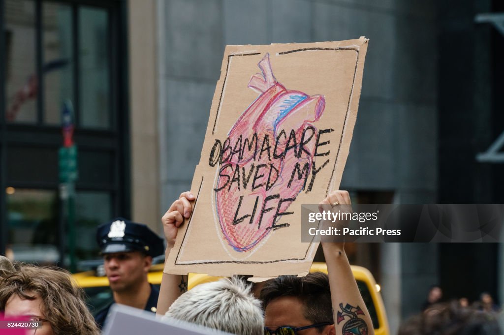 Participants hold signs while protesting the repeal and...