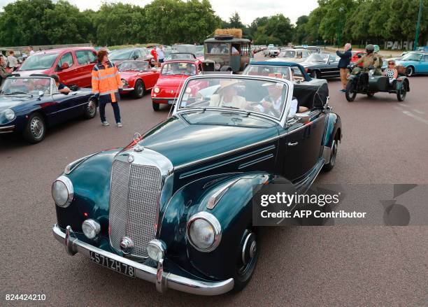Enthusiasts travel in a Mercedes as they take part in the "10th Vincennes en Anciennes" vintage vehicle parade at Chateau de Vincennes in Paris on...