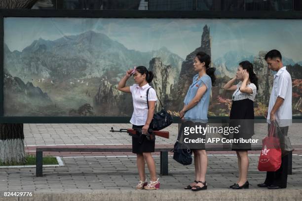 In this photo taken on July 29 a woman holding a mock rifle stands at a bus stop in Pyongyang. North Korea said July 30 its latest ICBM test was a...