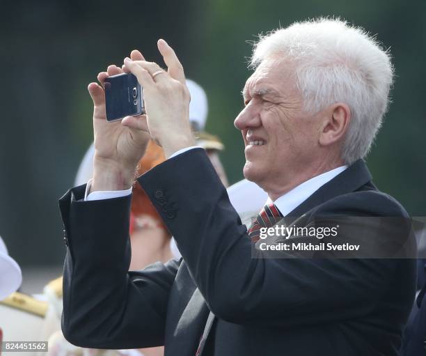 Russian billionaire, businessman Gennady Timchenko takes a photo as he watches the military parade on Neva river during the Navy Day celebration on...