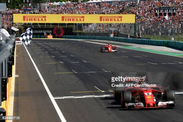 Ferrari's German driver Sebastian Vettel drives over finish line during the Formula One Hungarian Grand Prix at the Hungaroring racing circuit in...