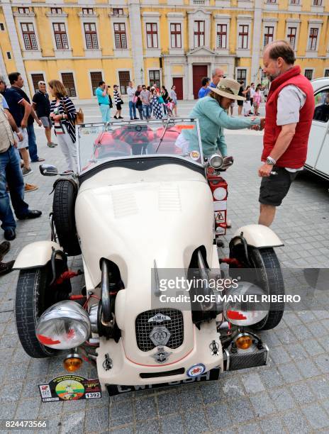 Participant helps his wife from a sport car 2CV version on the parking area in Mafra after the parade of Citroen classic cars 2CV during the World...