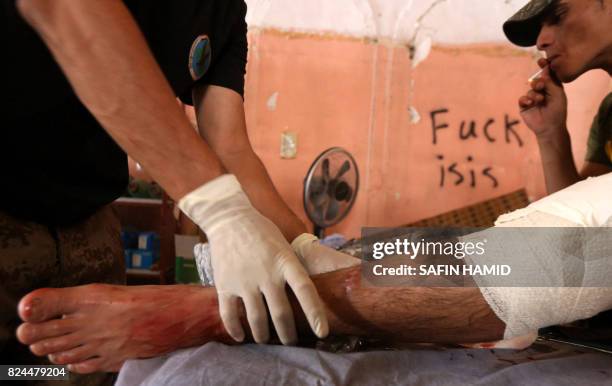 Member of the Iraq Couter-Terrorism service gives first aid to an injured man in western Mosul's old city on July 30, 2017.