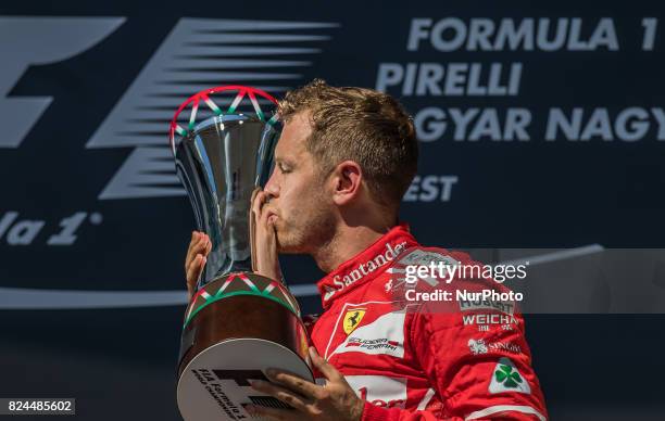 Sebastian Vettel of Germany and Scuderia Ferrari driver kiss the trophy on the podium at Pirelli Hungarian Formula 1 Grand Prix on Jul 30, 2017 in...