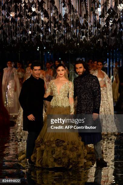 Indian bollywood actors Alia Bhat and Ranveer Singh present creations by Indian fashion designer Manish Malhotra during the FDCI India Couture week...