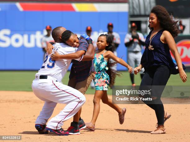 Adrian Beltre of the Texas Rangers hugs his son Adrian Jr. As Canila and Cassandra looks on in the fourth inning against the Baltimore Orioles at...