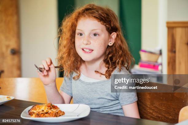 leuk roodharige meisje bezig met lasagne thuis eten. - lasagna stockfoto's en -beelden