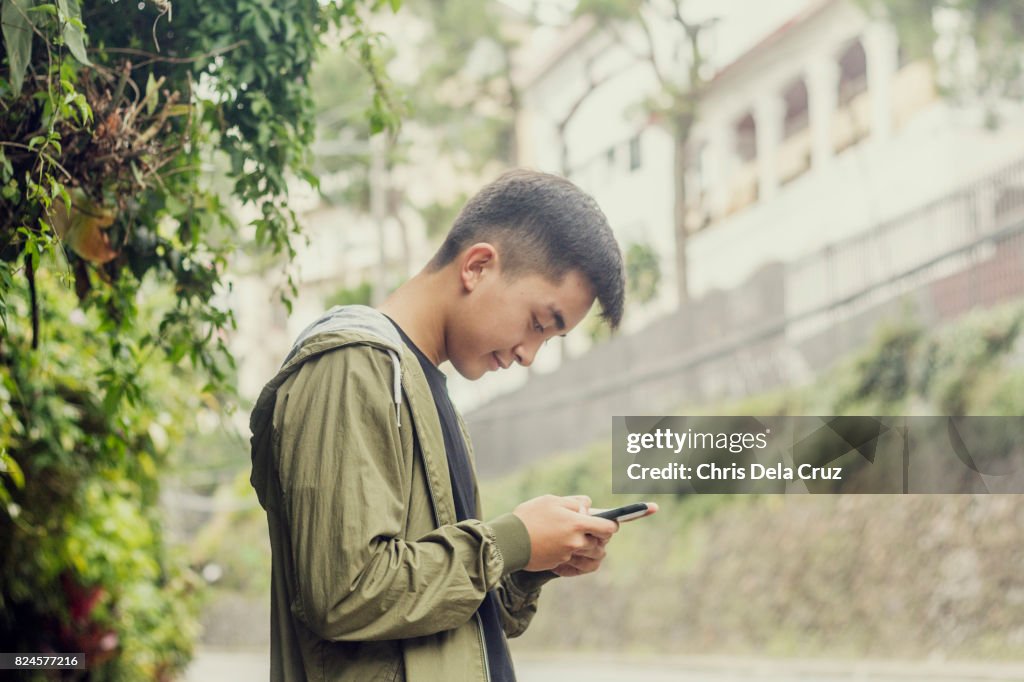 Young male adult texting on the street