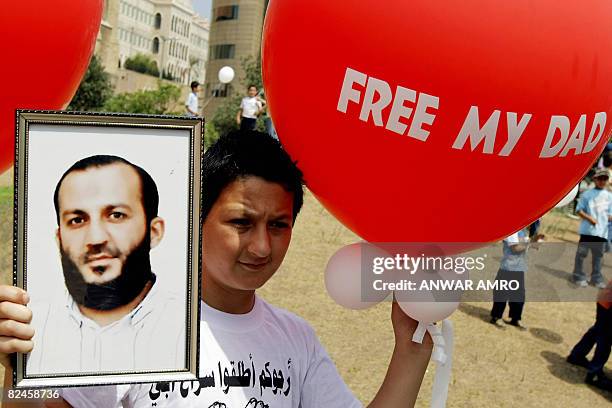 Lebanese boy hold an image of his father and a balloon that reads in Arabic, "Free My Dad" during a sit-in in front of the UN headquarters on August...