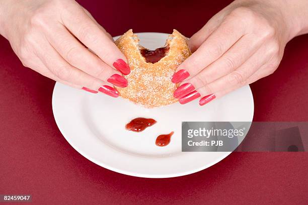 woman's hands holding jam doughnut, close-up - beignet fourré photos et images de collection