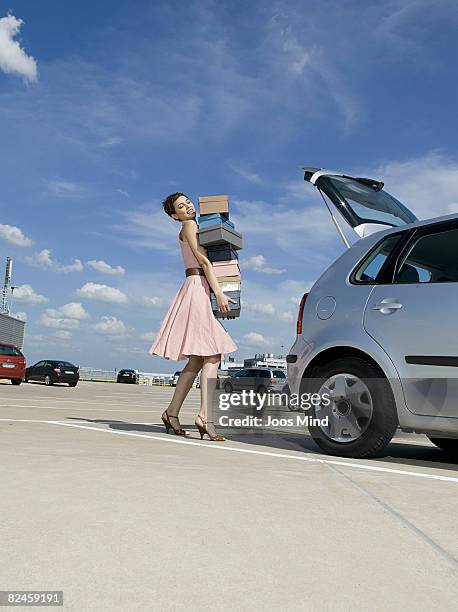 young woman carrying shoe boxes to trunk of car - shoes box stock-fotos und bilder