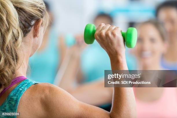 unrecognizable fitness instructor leads weight training class - hand weight stock pictures, royalty-free photos & images