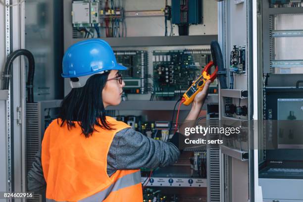 young female maintenance engineer testing voltage with digital multimeter - electrical equipment stock pictures, royalty-free photos & images