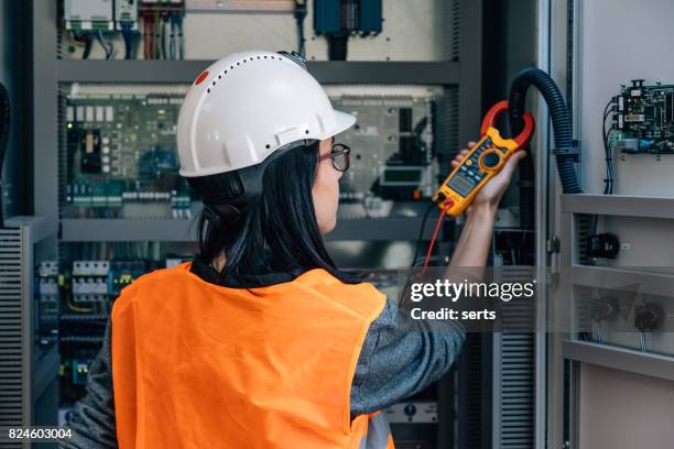 ingeniero de mantenimiento de hembra joven pruebas de voltaje con el multímetro digital - suministro de energía fotografías e imágenes de stock