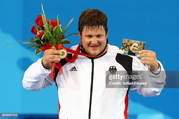 Matthias Steiner of Germany celebrates winning the gold medal in the Men's 105 kg group weightlifting event while holding a photo of his late wife...