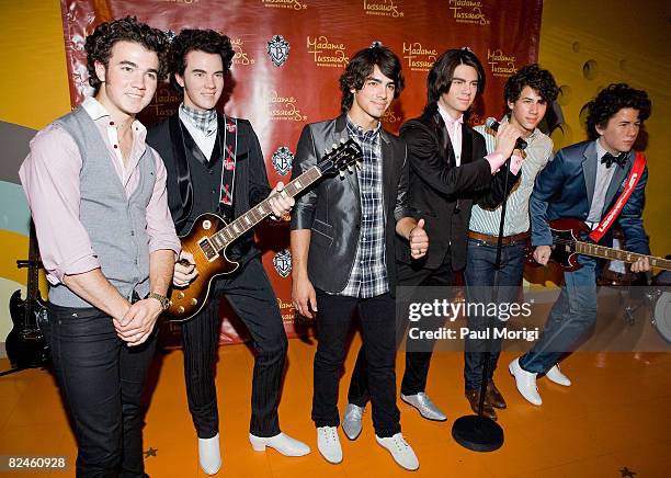 Kevin Jonas, Joe Jonas and Nick Jonas stand next to their wax likenesses at the unveiling of the Jonas Brothers Wax Figures at Madame Tussauds on...