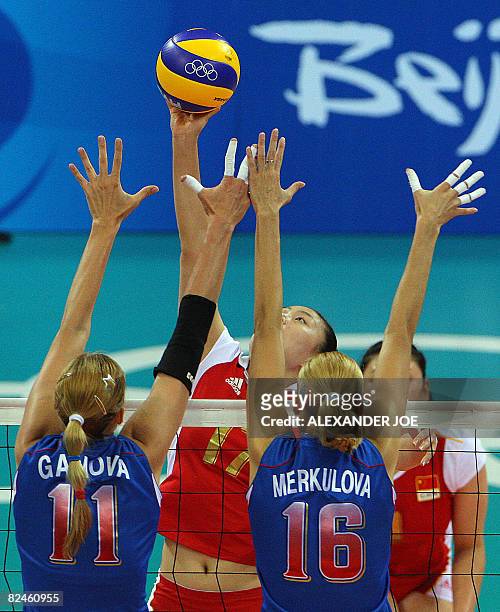 China Yunwen Ma performs a spike in front of Russia's Ekaterina Gamova and Yulia Merkulova during the women's quarterfinal volleyball match China vs....