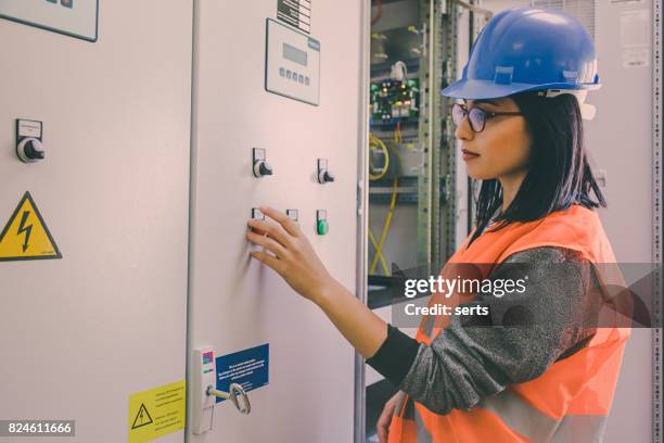 jonge vrouwelijke onderhoud ingenieur werken bij energie controlekamer - fuse box stockfoto's en -beelden