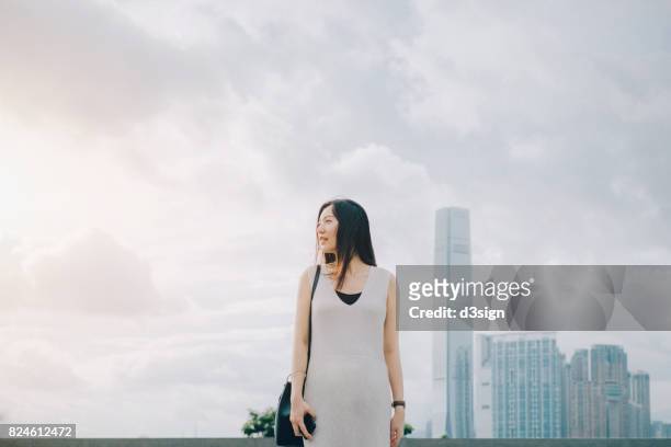beautiful young lady walking in city street against urban skyline - 見渡す ストックフォトと画像