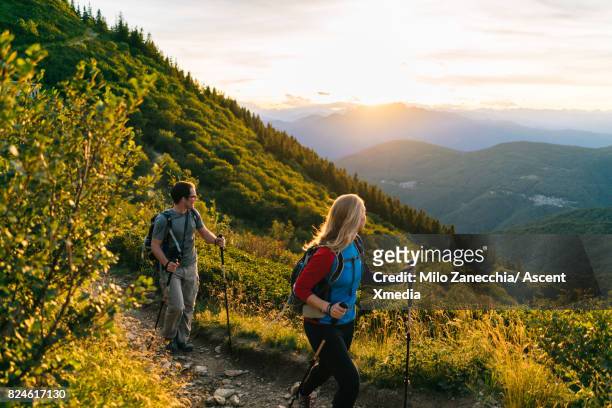 couple hike along trail at sunrise, mountains - escursionismo foto e immagini stock