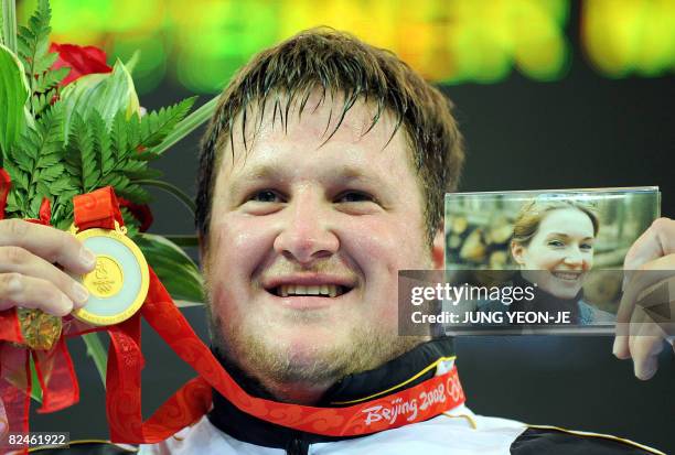 Gold medalist Matthias Steiner of Germany poses with a picture of his late wife Susann during the medal ceremony for the men's +105 kg weightlifting...