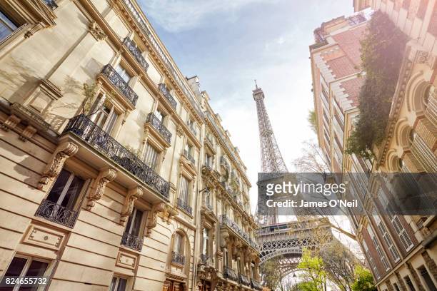 looking up at the eiffel tower through paris housing, paris, france - parigi foto e immagini stock