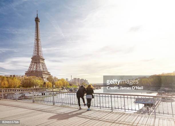 tourist couple looking at the eiffel tower, paris, france - paris france stock-fotos und bilder