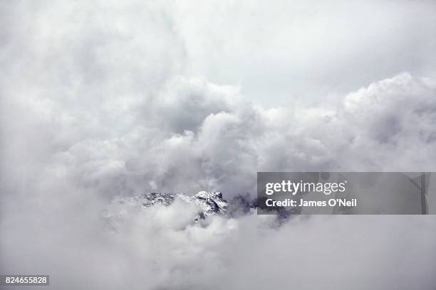 mountains emerging from stormy cloud - bedeckter himmel stock-fotos und bilder