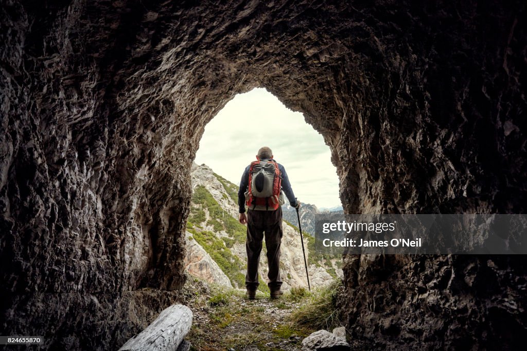 Hiker seen through mountain tunnel, dolomites, Italy