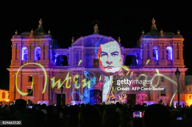 People gather in front of the Assumption Basilica Cathedral illuminated to celebrate the 150th anniversary of the birth of poet Ruben Dario during...