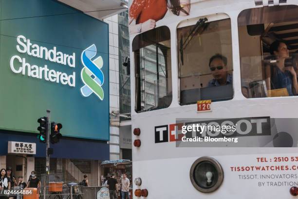 Tram drives past signage for Standard Chartered Plc displayed outside one of the bank's branches in Hong Kong, China, on Saturday, July 29, 2017....