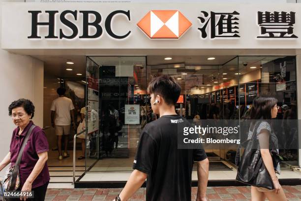 Pedestrians walk past an HSBC Holdings Plc bank branch in Hong Kong, China, on Saturday, July 29, 2017. HSBC is set to announce plans to buy back $2...