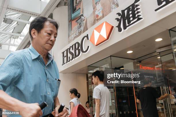 Pedestrians walk past an HSBC Holdings Plc bank branch in Hong Kong, China, on Saturday, July 29, 2017. HSBC is set to announce plans to buy back $2...