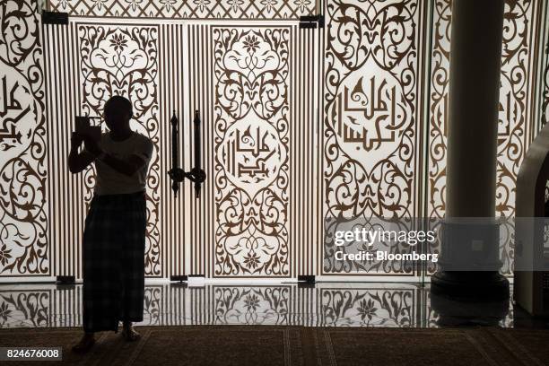 Visitor is silhouetted while using a smartphone to take a photograph at the Crystal Mosque in Kuala Terengganu, Terengganu, Malaysia, on Monday, July...