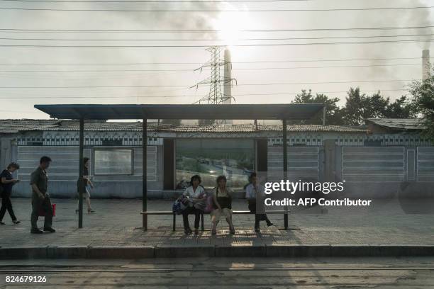 In a photo taken on July 24 people wait at a trolley bus stop before a power station in Pyongyang. Buses and trams are by far the most common means...