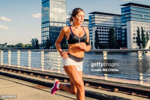 photo of a woman running while sun is setting - running shorts stockfoto's en -beelden