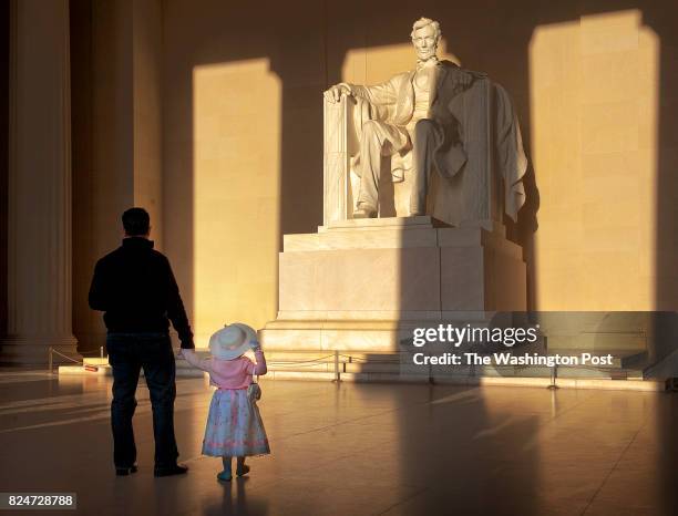 Washington, DC Elise Martinez, 2&1/2, clutches her fathers' hand while watching the suns' rays light up Abraham Lincoln during the annual sunrise...