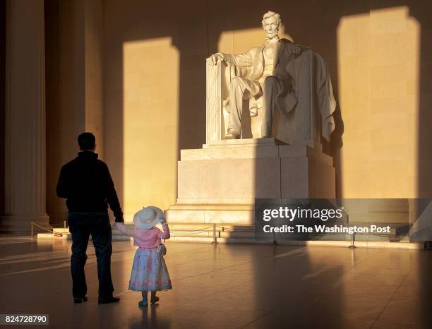 Washington, DC Elise Martinez, 2&1/2, clutches her fathers' hand while watching the suns' rays light up Abraham Lincoln during the annual sunrise...