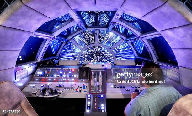 Danny Handke, a creative design executive with Walt Disney Imagineering, demonstrates the hyper reality of the cockpit in the Star Wars Millennium...