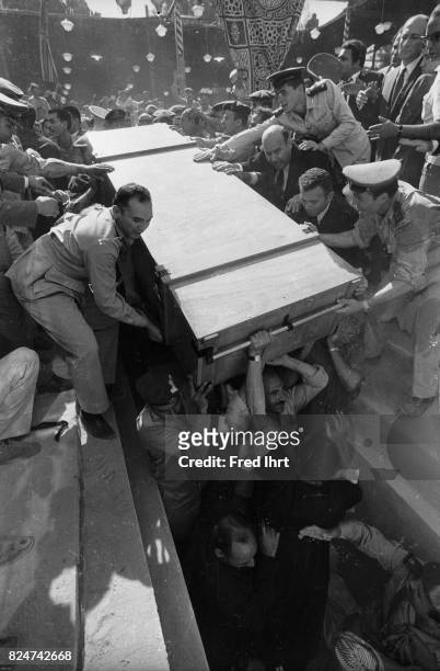 Presidents Gamal Abd al-Nasser coffin getting lifted into it´s final place. Crowds are in the way. Soldiers help to hold back the crowd. People are...