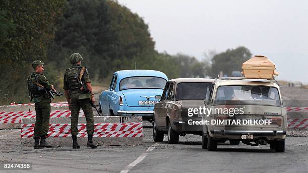 Russian soldiers look at a car carring a coffin at a checkpoint on the Gori-Tbilisi road near the village of Khurvaleti on August 20, 2008. Russian...