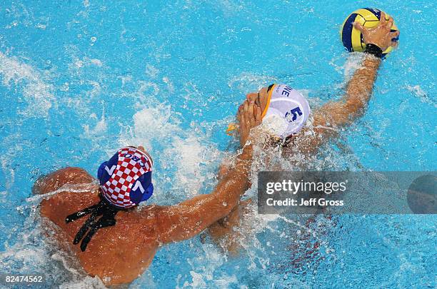 Nikola Janovic of Montenegro is challenged by Mile Smodlaka of Croatia in the Men's Quarter Final in the water polo event at the Olympic Sports...