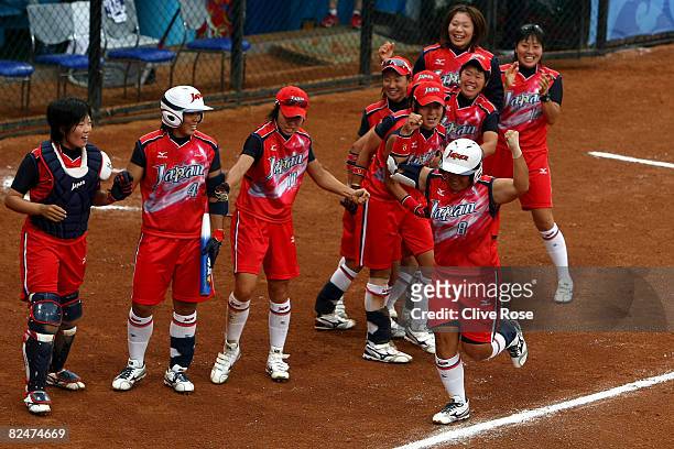 Megu Hirose of Japan celebrates as she runs by here team mates on the way to home plate and scores on her 2-run home run in the fourth inning against...