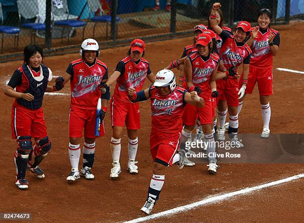 Megu Hirose of Japan celebrates as she runs by here team mates on the way to home plate and scores on her 2-run home run in the fourth inning against...